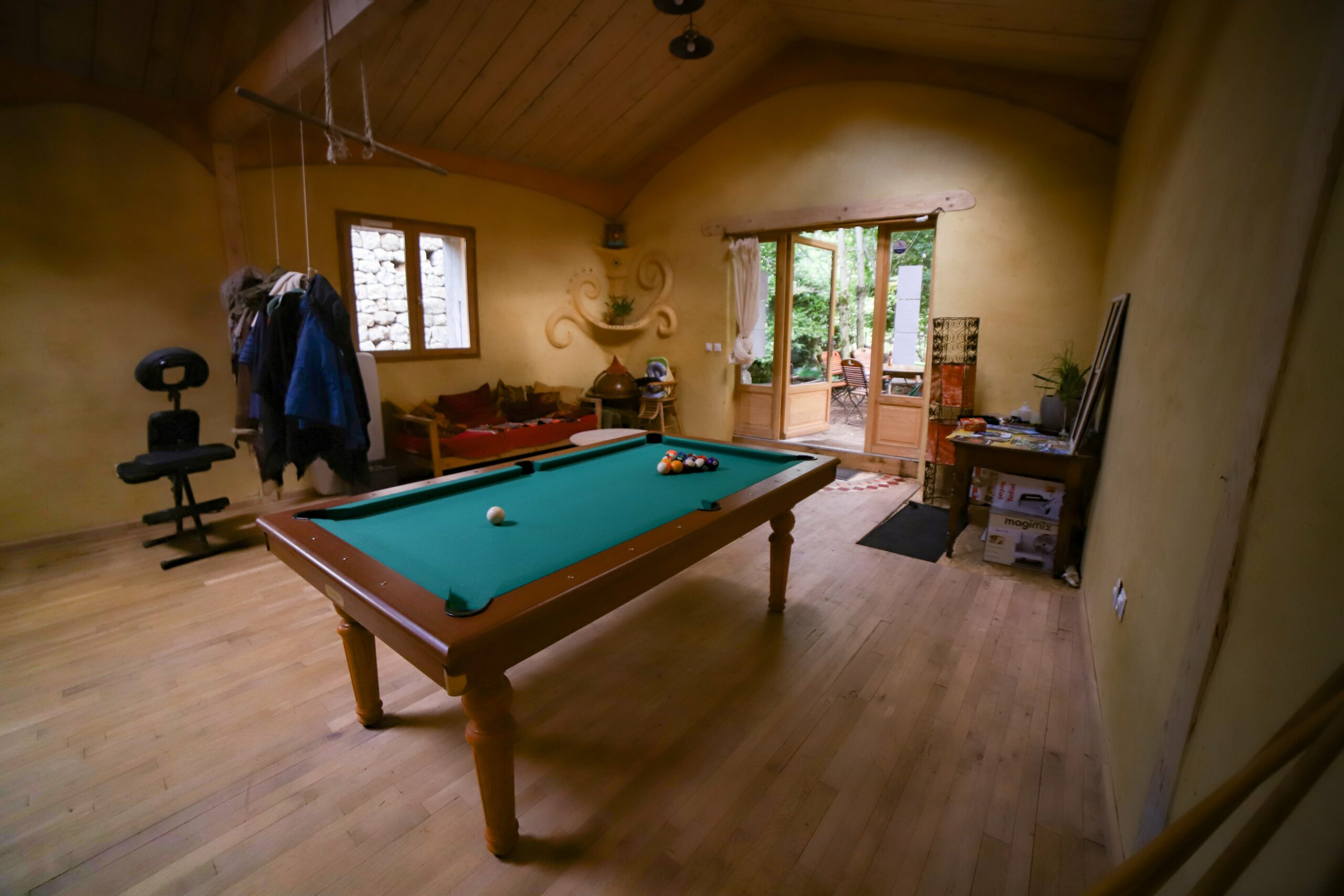 page-espace-camping-aupres-de-mon-arbre-grande-salle-billard-jeu-de-societe-min Grande salle avec poêle à bois et scène, camping Auprès de mon arbre, Ardèche